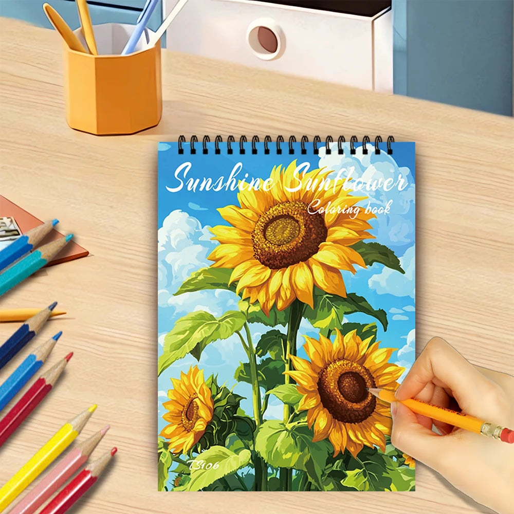 A spiral coloring book featuring illustrations of sunflowers and clouds on a wooden table.