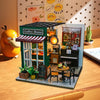 A handmade wooden miniature dollhouse kit featuring a green coffee house with an awning and interior details.