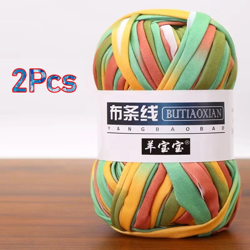 A skein of multi-colored soft chunky t-shirt yarn in shades of green, yellow, and pink is shown.