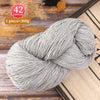 A ball of gray premium alpaca blend yarn is shown on a wooden surface.