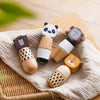 A set of wooden animal puzzle toys featuring panda, bear, and monkey figures resting on a beige linen cloth.