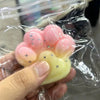 A hand holds a pink squishy product with yellow accents and glitter inside clear plastic packaging.