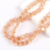 A strand of amber colored glass star spacer beads laid out on a white surface.