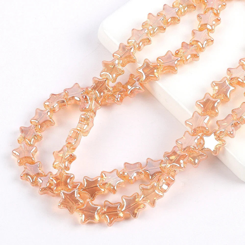 A strand of amber colored glass star spacer beads laid out on a white surface.