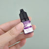 A hand holds a small dark bottle of violet liquid candle dye labeled Violet for DIY wax projects.