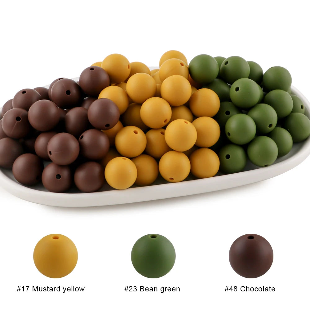 A collection of round silicone beads in mustard yellow, bean green, and chocolate brown.