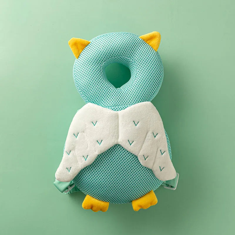 A soft baby head protector pillow shaped like an owl with yellow ears and white wings against a light green background.