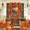 An autumn decor display featuring an artificial maple leaf garland, pumpkins, and fall foliage arranged around a wooden door.