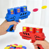 A hand holds a blue toy gun with EVA foam bullets, next to a pile of colorful foam discs.
