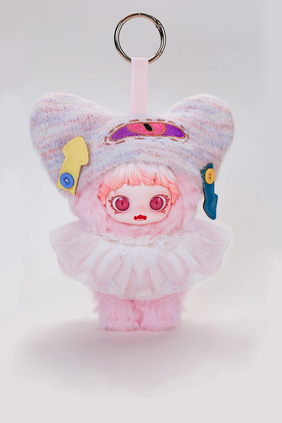 A fluffy pink plush doll with purple ears and pink hair, featuring gold and blue accessories.