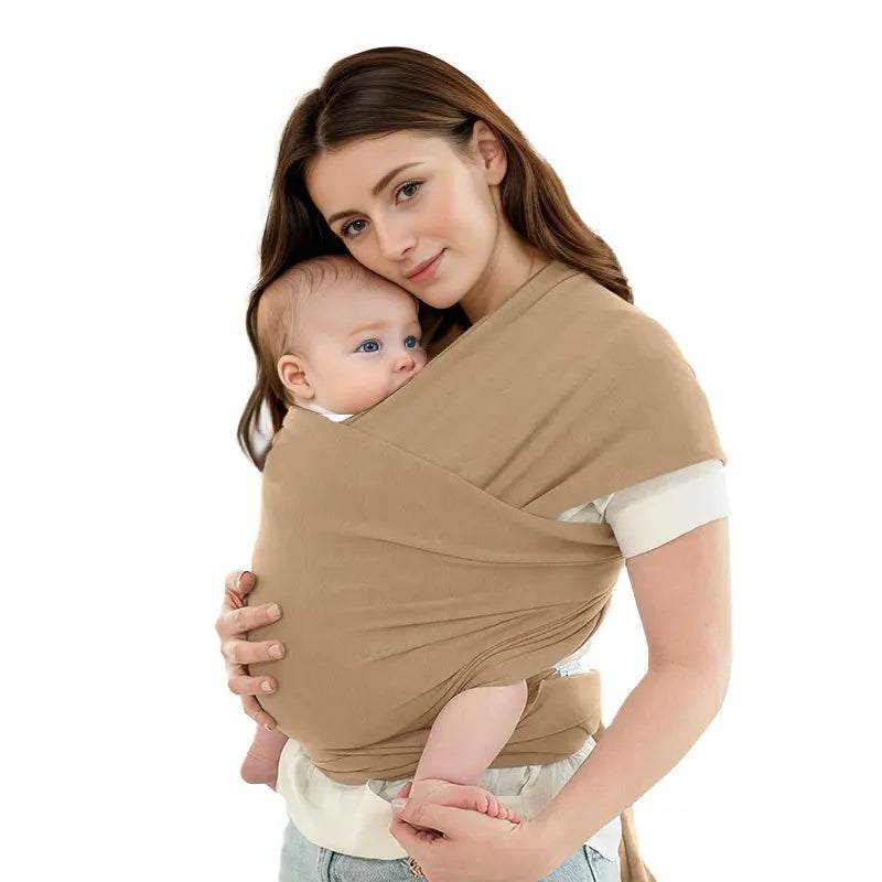 A woman is wearing an ergonomic baby sling carrier while holding a baby.