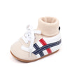 A pair of beige ankle-hugging baby booties with white laces and navy and red stripes on the toe area.