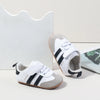 A pair of white baby first walkers shoes with black and gray stripes resting on a white background.
