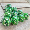 A collection of ten green pearl acrylic D20 dice scattered on a wooden surface.