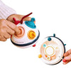 A hand is holding a colorful pop-up animal toy designed for cause and effect learning.