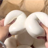 Hands are squeezing a white yogurt cake squishy stress relief toy.