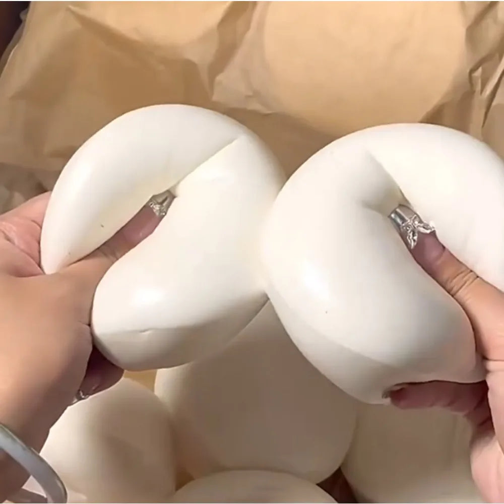 Hands are squeezing a white yogurt cake squishy stress relief toy.