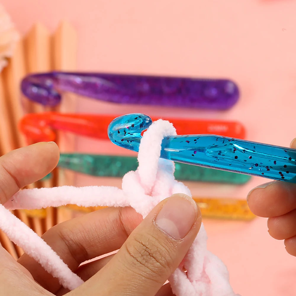 A hand is holding a blue crystal crochet hook, demonstrating the transparent crystal crochet hook set.