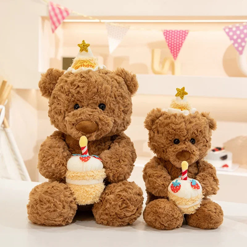 A brown teddy bear plush toy with a birthday hat and an eye mask, sitting next to a small cake.