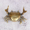 A brass crab figurine statue with detailed claws and body, displayed against a light gray background.