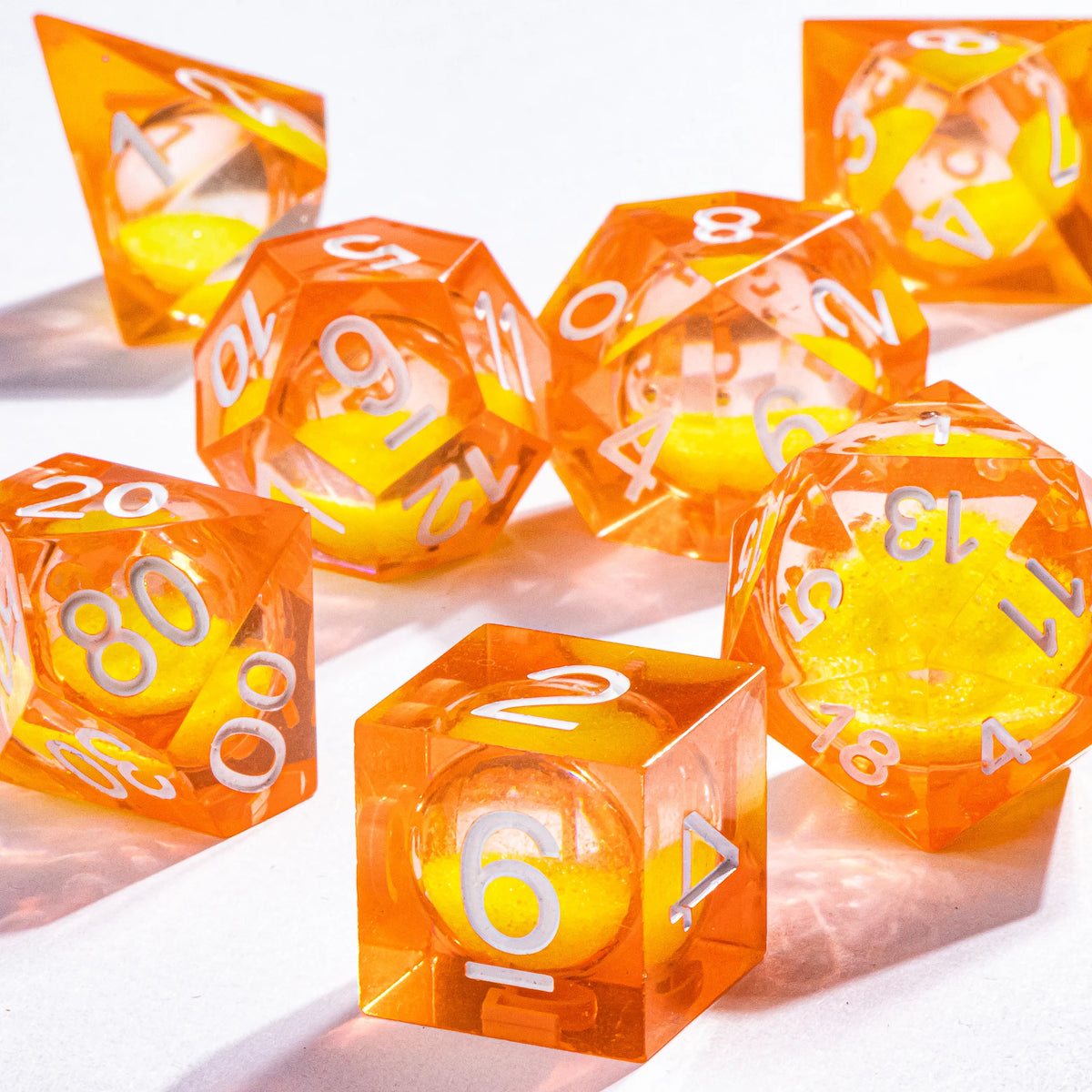 A collection of orange liquid core polyhedral dice showing various numbers and a galaxy finish.