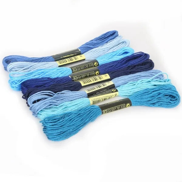 A set of multicolor embroidery floss skeins in various shades of blue and purple with a glitter finish.
