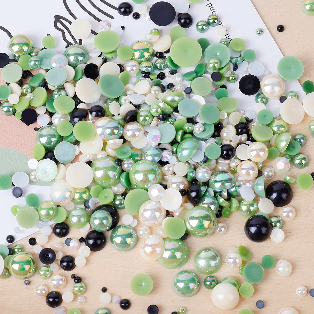A scatter of mixed resin rhinestone pearls in various shades of green, white, and black.