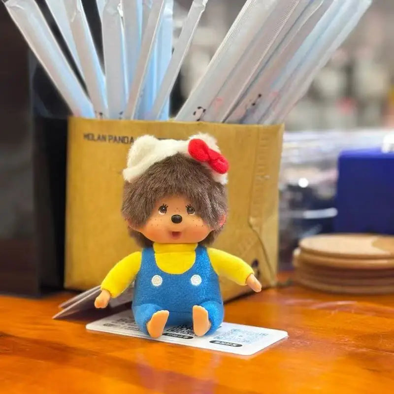A small brown plush monkey with a white headband and red accent, sitting on a wooden surface.