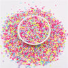 A bowl filled with colorful polymer clay slice sprinkles for slime and DIY crafts scattered on a white surface.