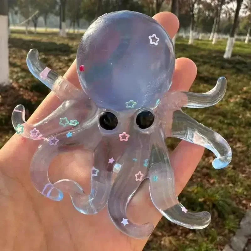 A clear silicone octopus squishy toy with purple and pink accents is held in a hand.