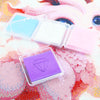 A collection of diamond painting clay in various colors, including purple, pink, and blue, displayed on a colorful background