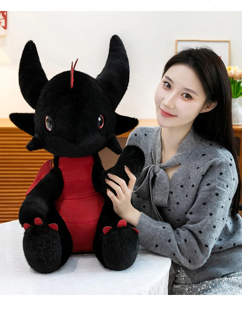 A woman is holding a black Toothless Dragon plush toy in a studio setting.