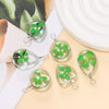 A set of handmade glass four leaf clover pendants with silver jump rings displayed on a light background.