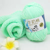 A ball of light green pre-dyed milk cotton yarn with a label in Japanese and English is shown next to a rolled skein.