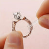 A hand holds an adjustable ring sizer pad for jewelry, showing the clear plastic and metal ring design.
