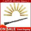 A pack of ten yellow and natural wood clarinet reeds arranged in a semi-circle with a silver instrument shown below.