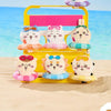 A yellow plastic container holds several cute Chiikawa summer swimming ring plush keychains on a sandy beach.