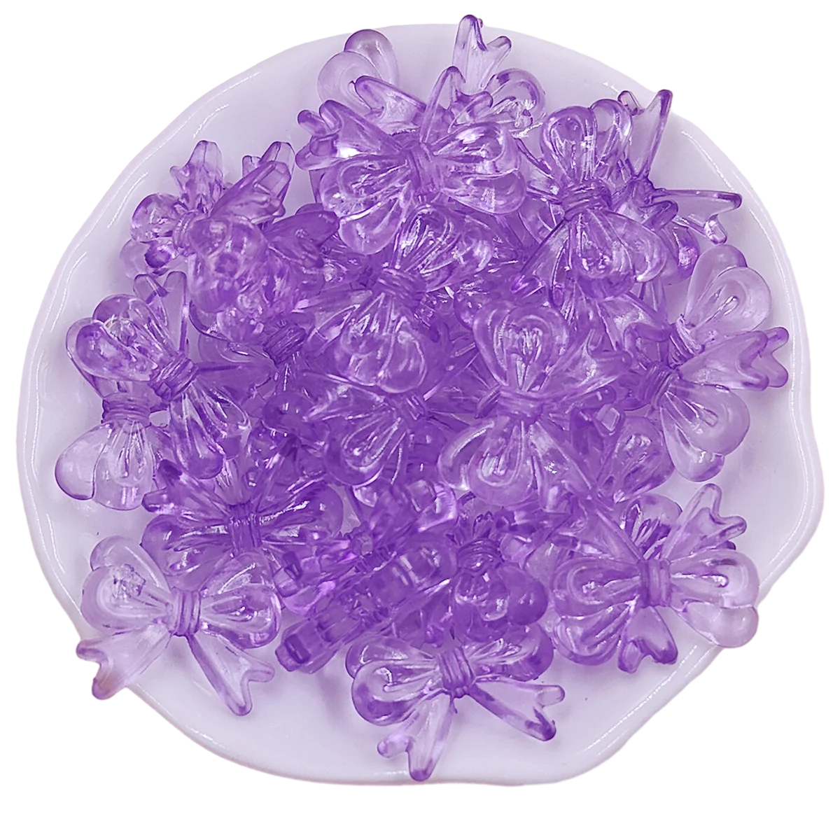 A pile of 20 clear purple acrylic bow beads for jewelry making displayed on a white dish.