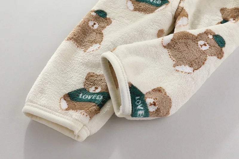 A beige fleece jacket and pants set featuring a repeating pattern of brown bears with green accents.