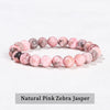A bracelet made of natural pink zebra jasper beads, showing various shades of pink and gray.