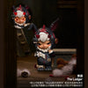 A dark-colored collectible figure blind box featuring a mischievous cat character with white fur and red accents.