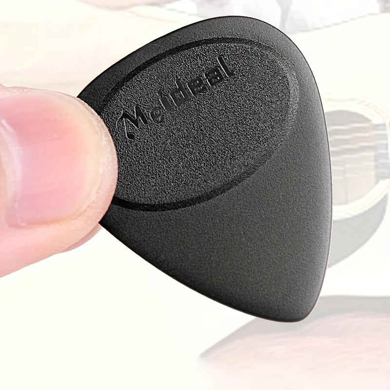 A close-up of a black guitar pick with an anti-slip grip, held between fingers.