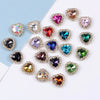 A collection of heart-shaped flatback sew-on rhinestones in various colors and clear stones scattered on a white background.