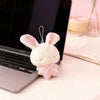 A white plush bunny keychain with pink embroidered ears and a pink checkered bow resting on a laptop.