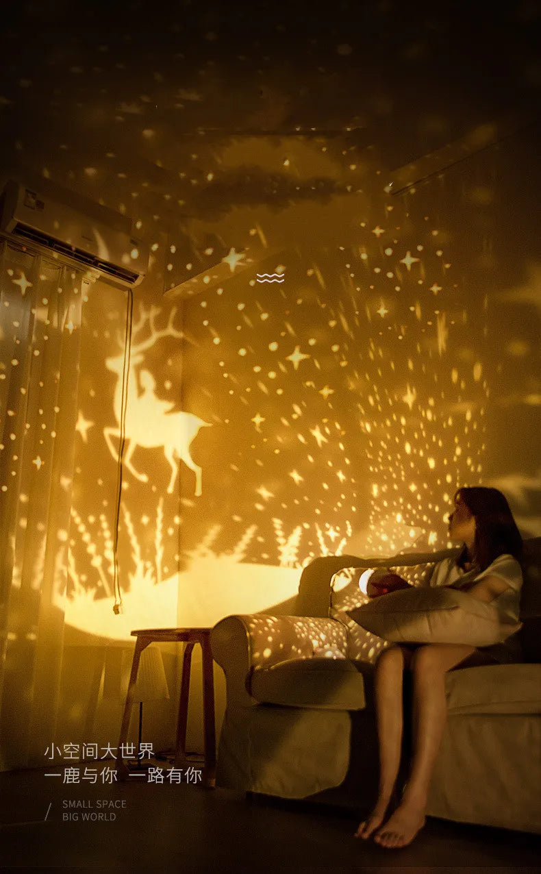 A person sits in a dimly lit room illuminated by a yellow starry projector casting light patterns on the wall.