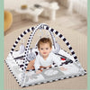 A baby is sitting inside a white and black striped play mat with a fitness frame and hanging toys.