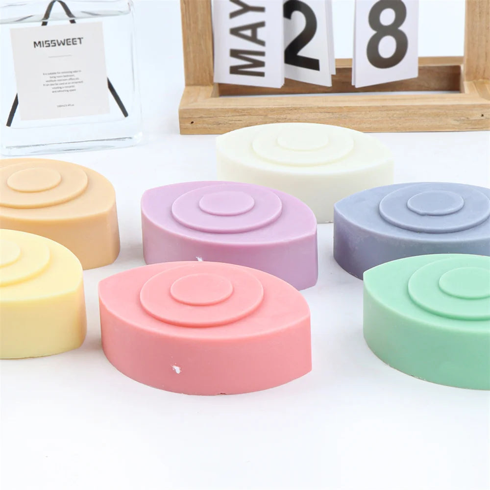A collection of round silicone molds in various pastel colors including pink, purple, yellow, and green for candles, soap, an