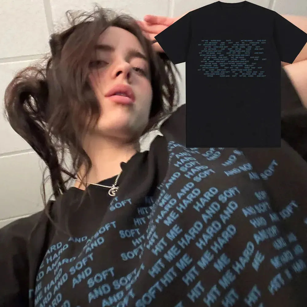 A person wearing a black t-shirt featuring the Hit Me Hard and Soft Tour design.