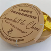 A 3D-printed polygonal die labeled Loch's Fromagerie with a cheese dice set and carrying case.
