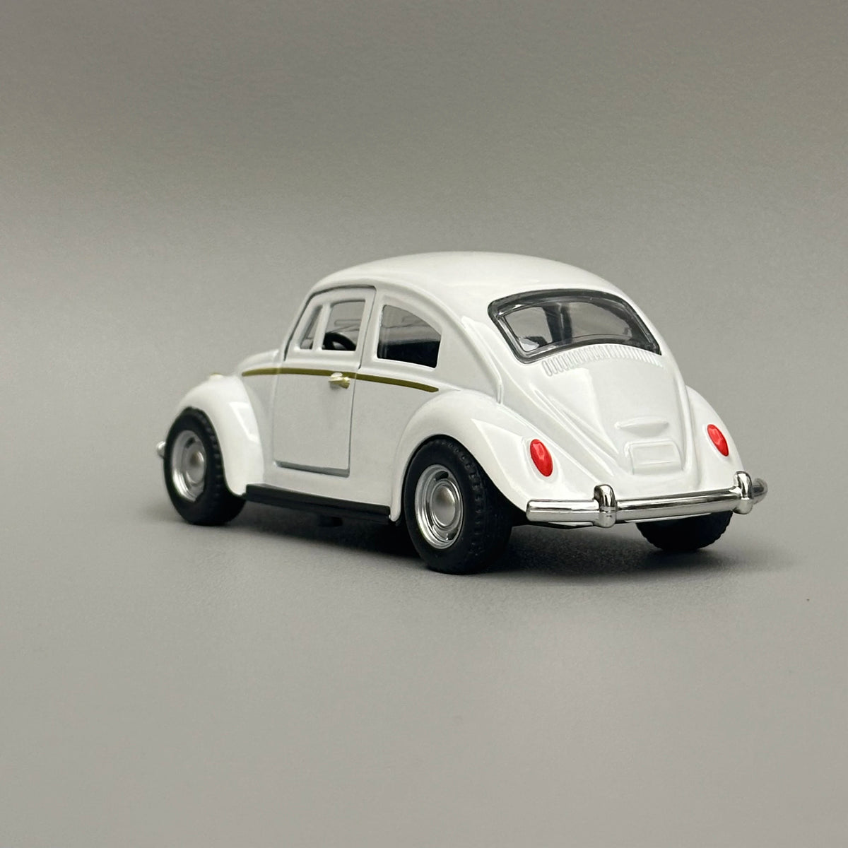 A white diecast model of a classic retro Beetle with gold trim, shown from the side.
